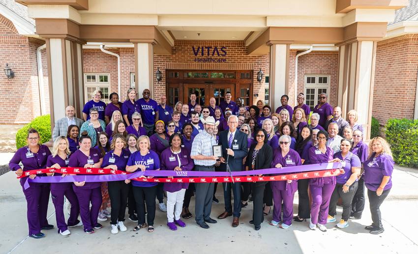 A large group in front of the VITAS IPU holding the ceremonial purple ribbon to open the facility