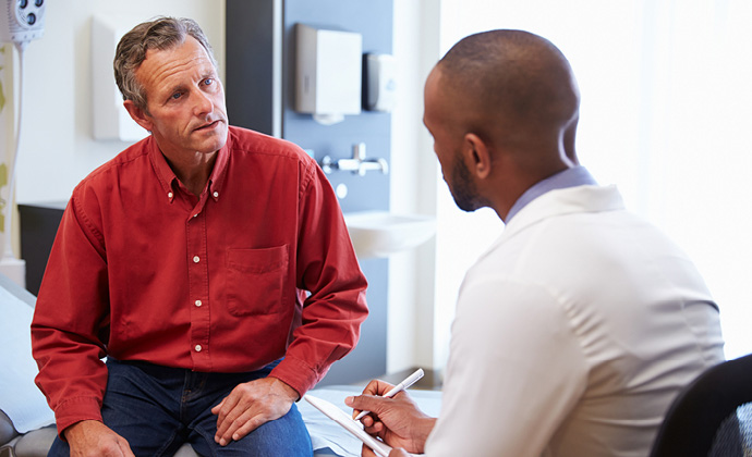 A physician talks with a man in an exam room